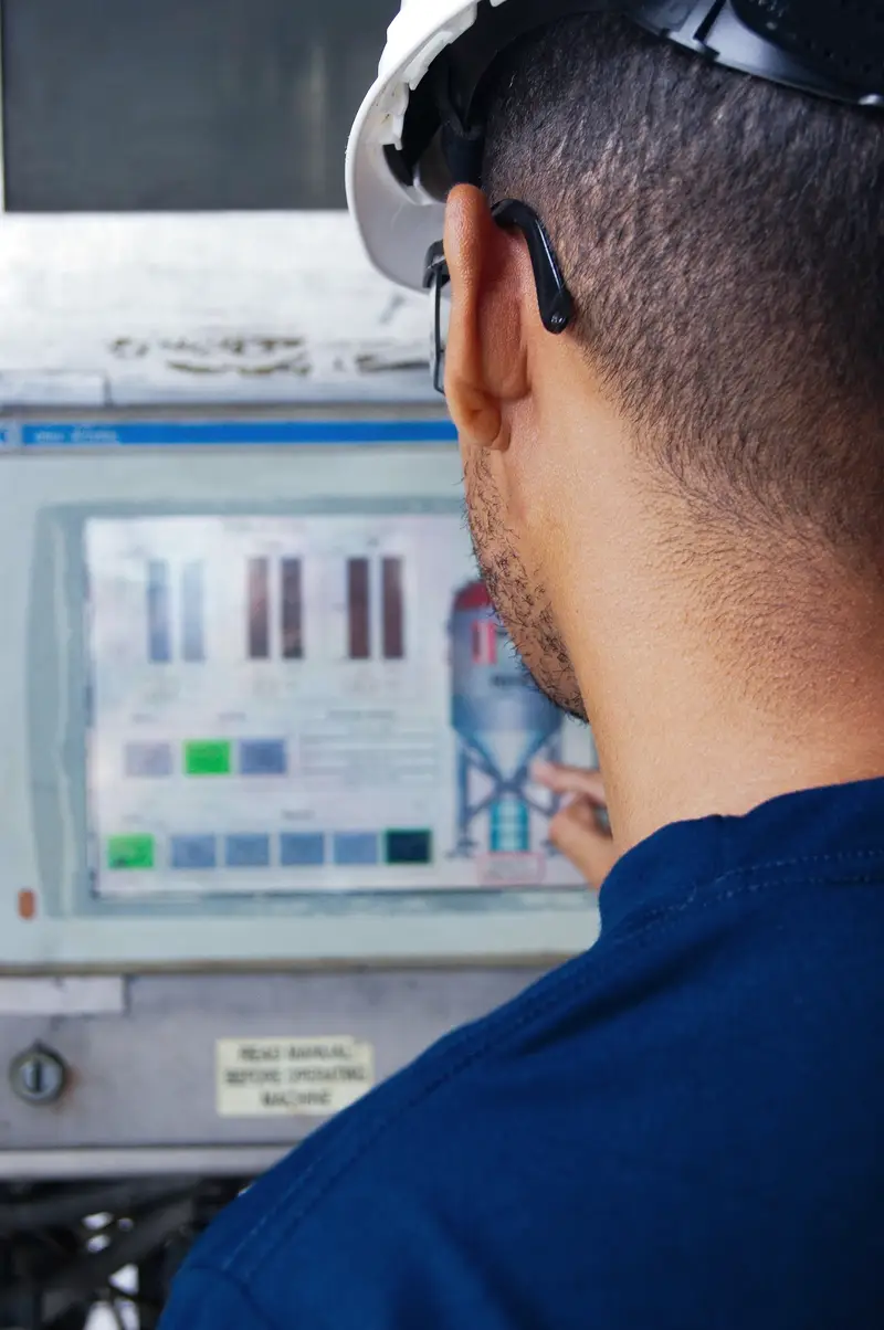 Tecnico al pannello di controllo di un impianto industriale
